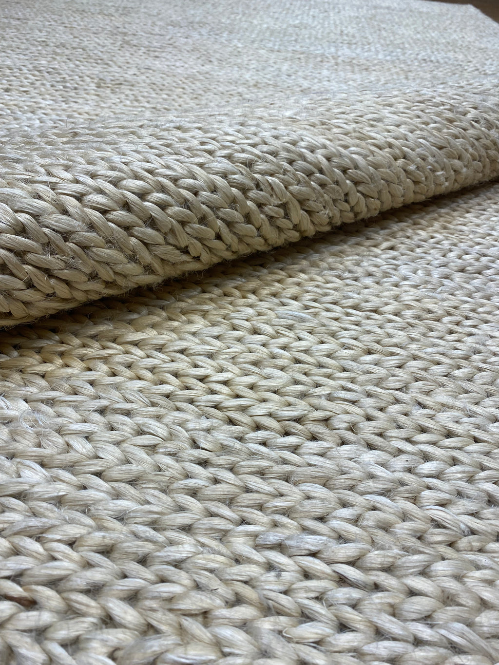 Ziegler & Co. Modern Rug features a thick, braided texture in neutral tones, shown here rolled partially to display details.