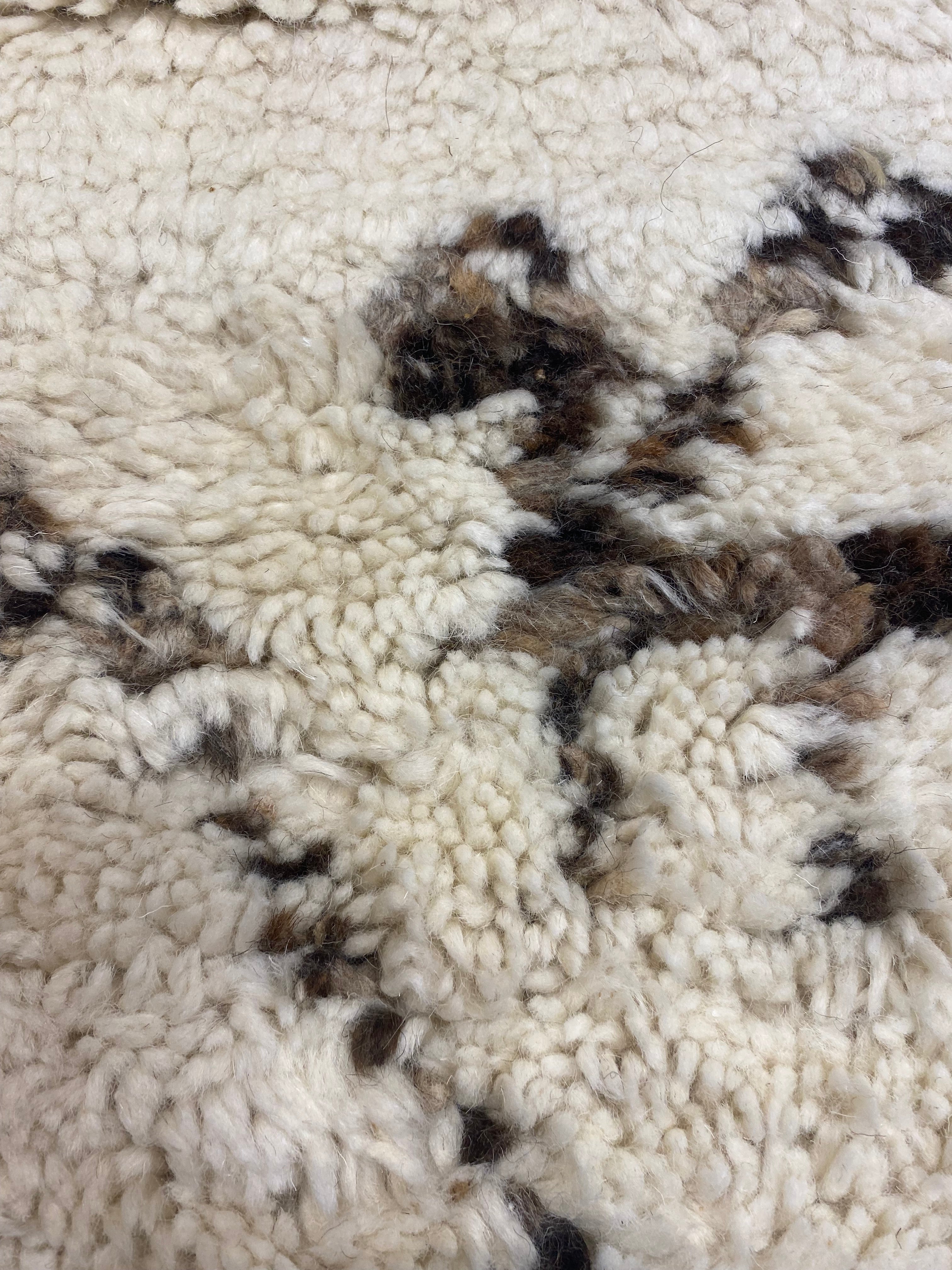 Close-up of Santa Barbara Chic Moroccan rug with a textured, cream-colored background and brown abstract patterns.